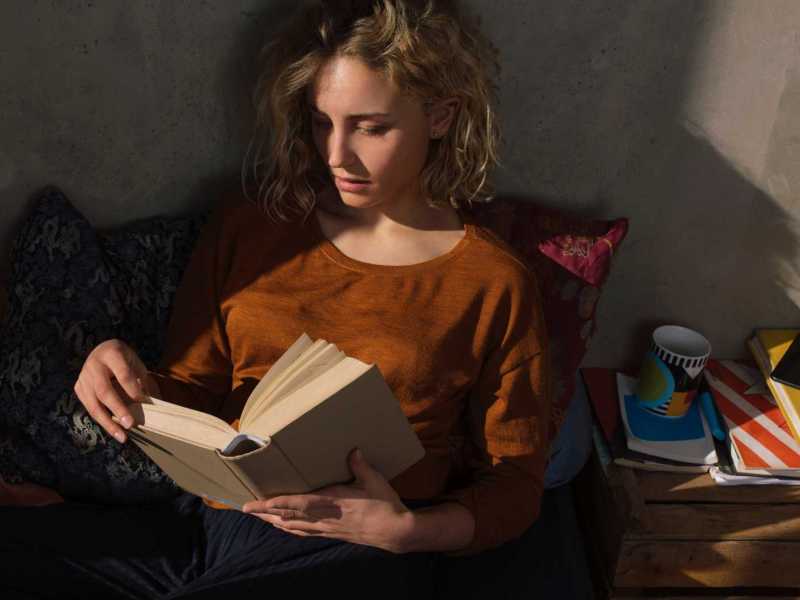 Blonde Frau liest einen Thriller im Freien. Dunkle Atmosphäre.