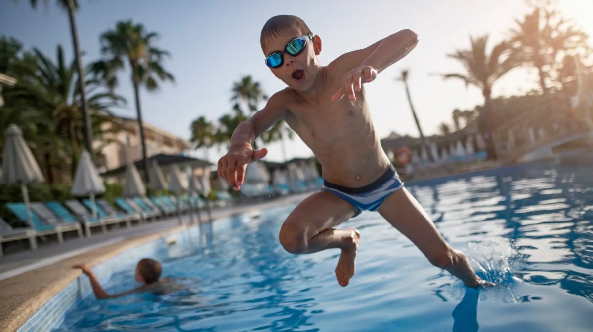 Junge, ca 7 Jahre alt, albert im Freibad herum.
