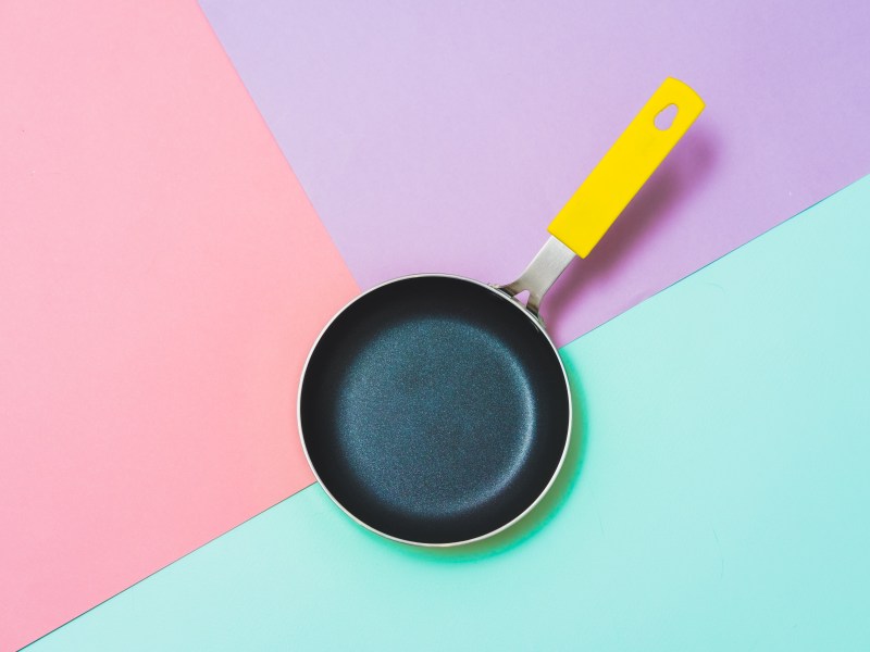 Pfanne mit Loch im Griff auf dreifarbigem Hintergrund