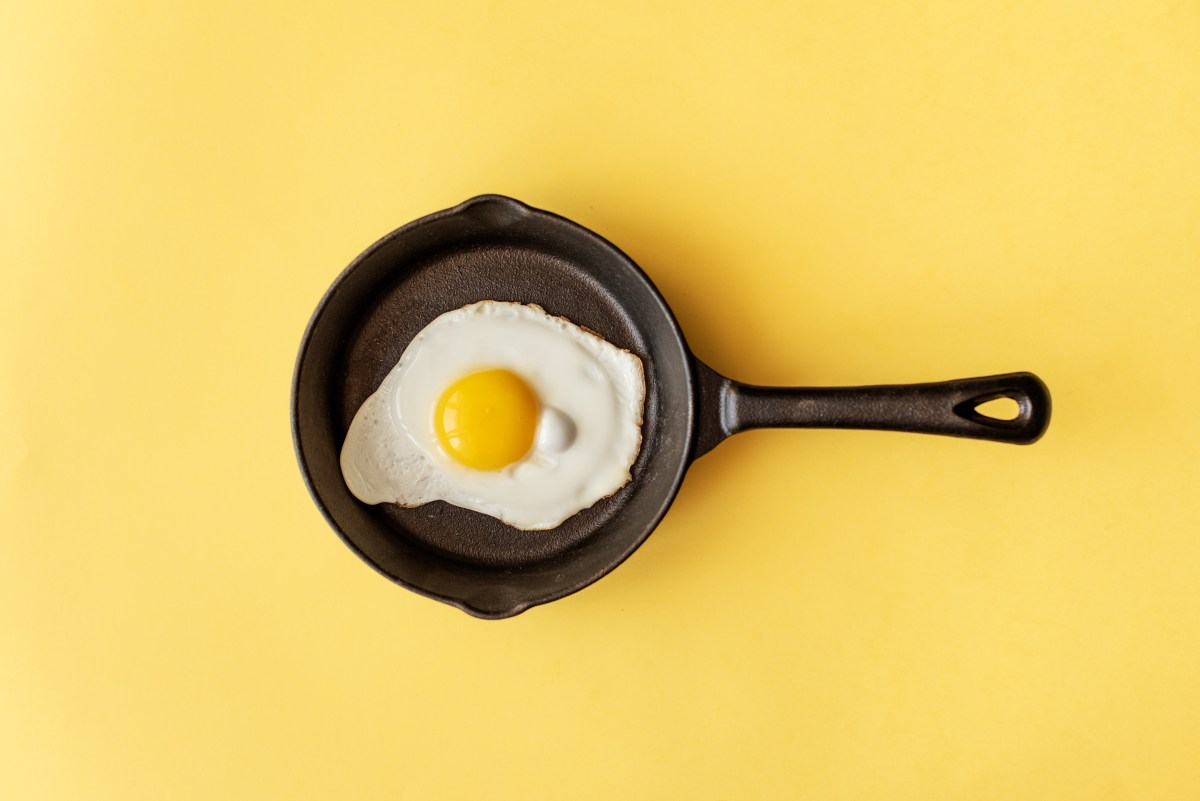 schwarze Pfanne mit Spiegelei auf gelbem Hintergrund