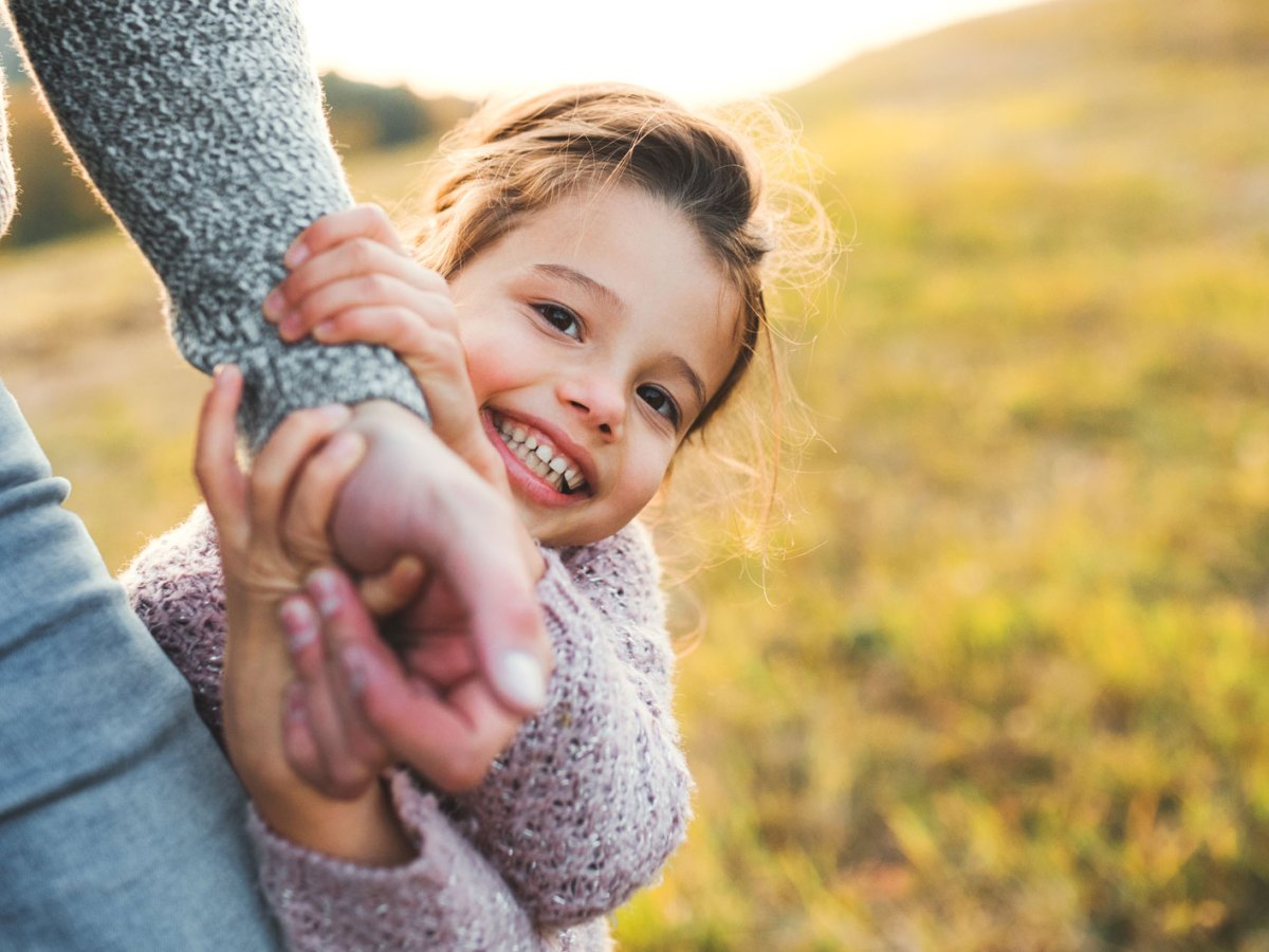 Kleines Mädchen hält draußen die Hand ihres Vaters.