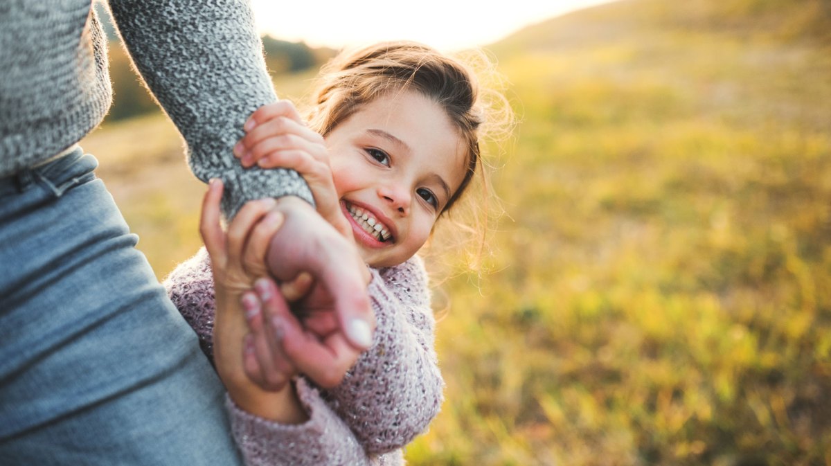 Kleines Mädchen hält draußen die Hand ihres Vaters.