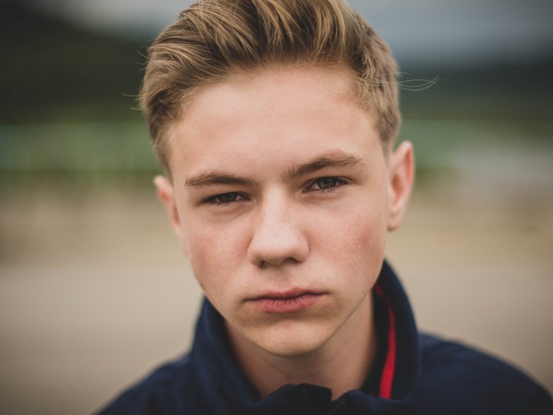 Poträt eines ernst bis wütend schauenden Teenagers draußen.