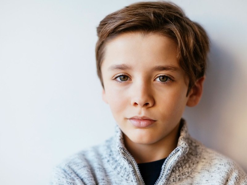 Poträt eines Jungen, ca. 10 Jahre alt, der skeptisch in die Kamera schaut.