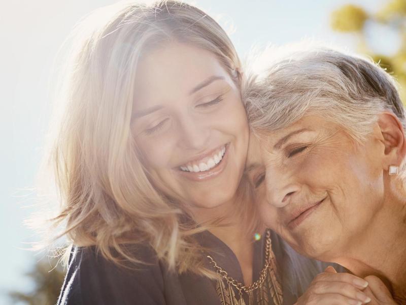 Mutter mit ihrer erwachsenen Tochter umarmen sich innig.