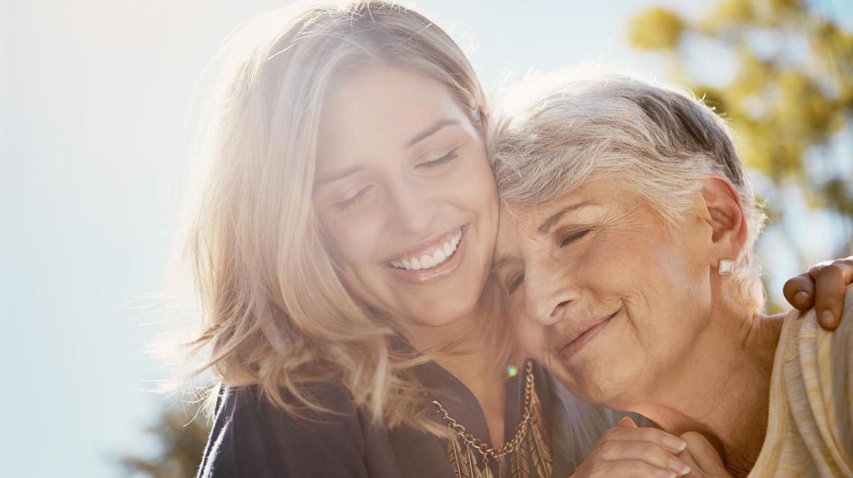 Mutter mit ihrer erwachsenen Tochter umarmen sich innig.