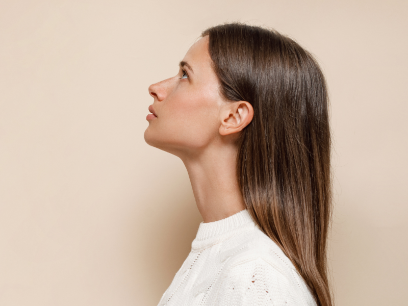 Frau blickt seitlich mit dunklen, glatten, langen Haaren nach oben