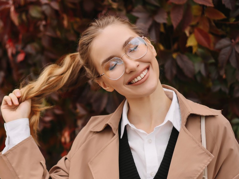 Frau mit herbstlichen Hintergrund, die einen Trenchcoat trägt