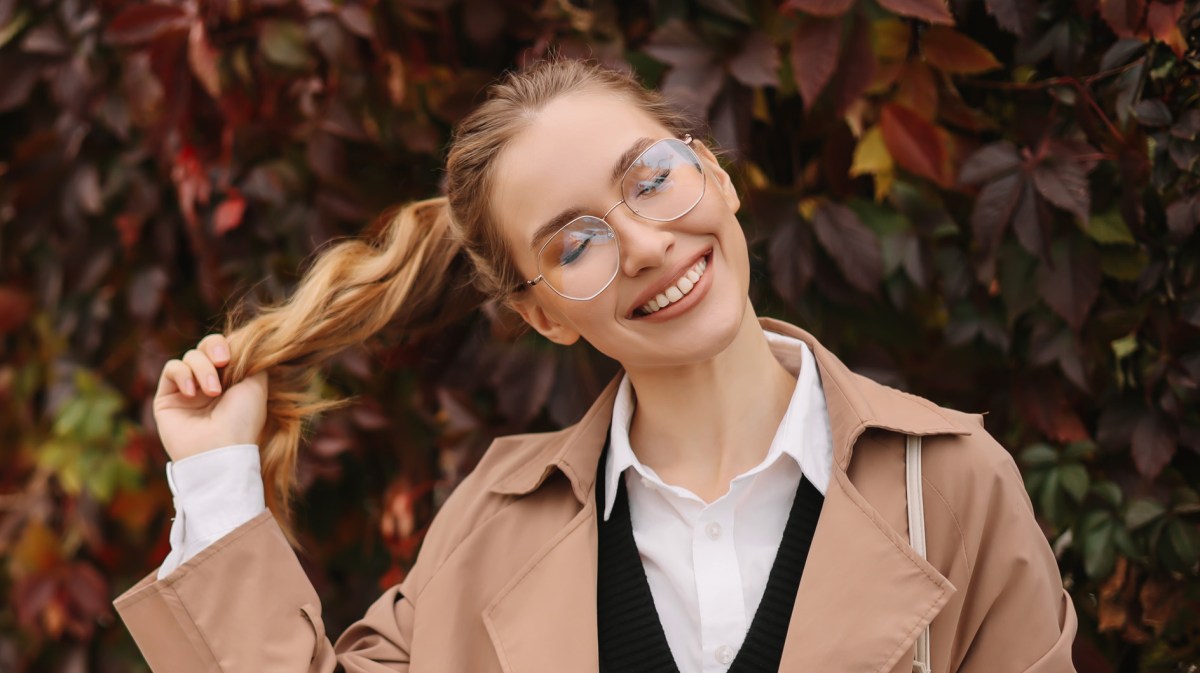 Frau mit herbstlichen Hintergrund, die einen Trenchcoat trägt