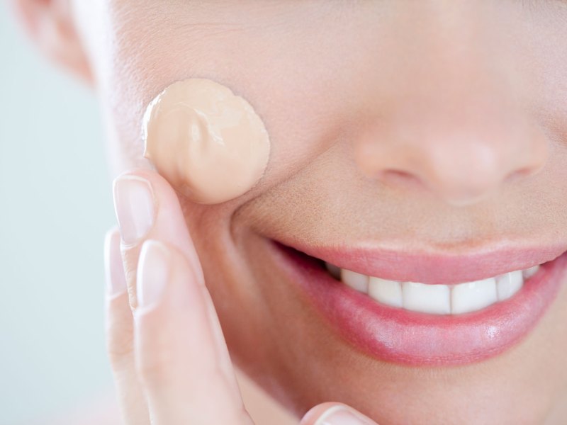 Frau mit einem Tropfen flüssigem Make-up im Gesicht