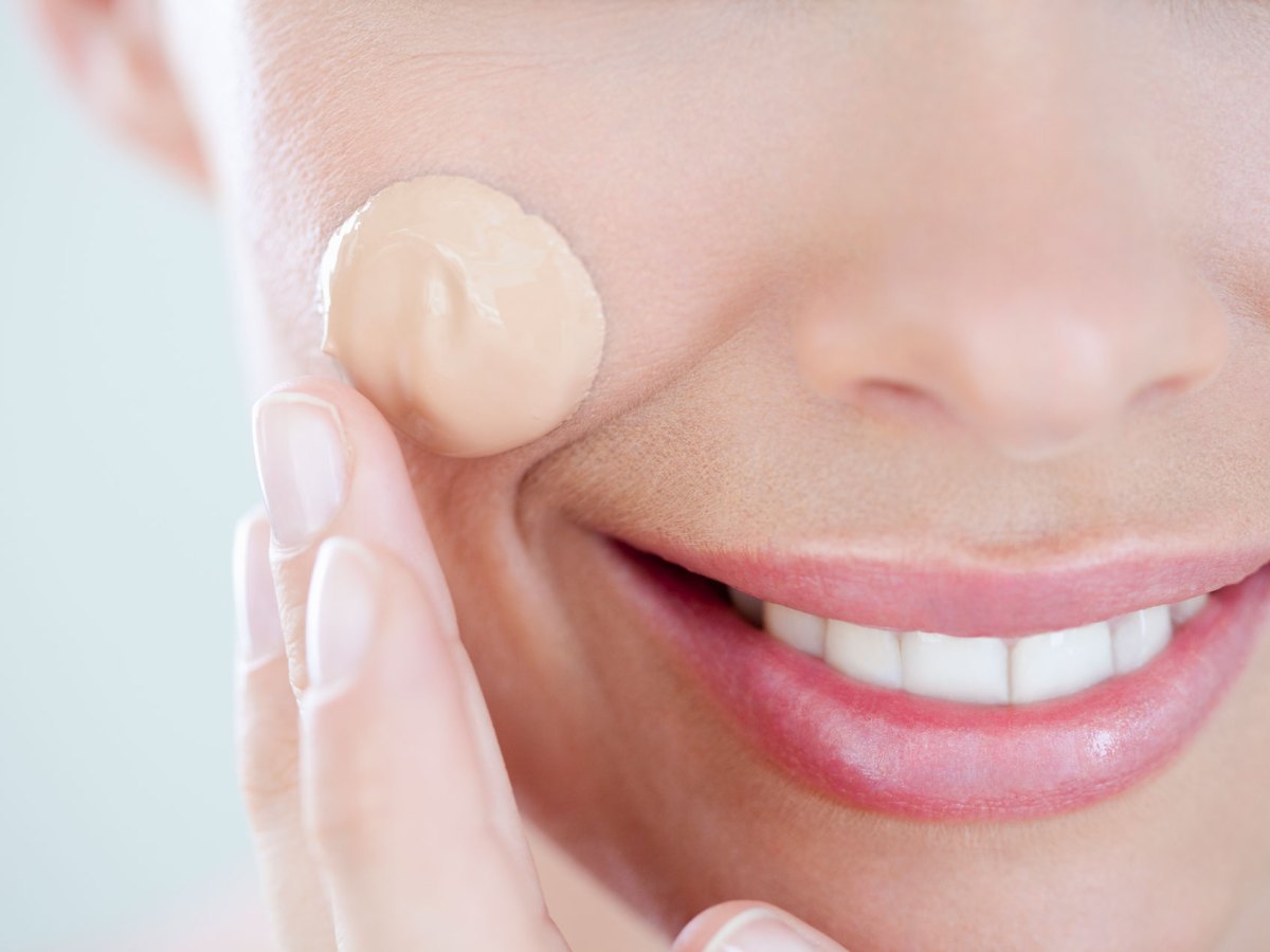 Frau mit einem Tropfen flüssigem Make-up im Gesicht