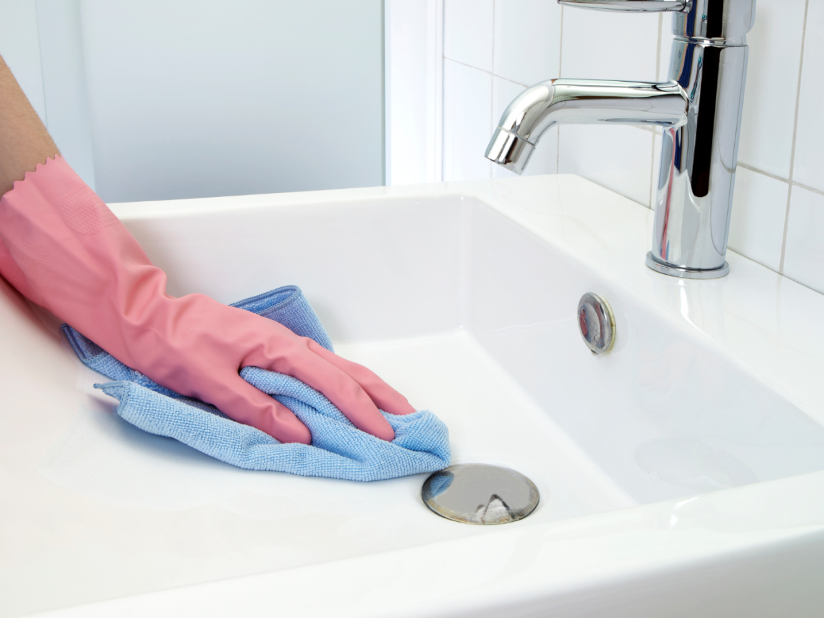 Frau, die das Waschbecken im Bad putzt.