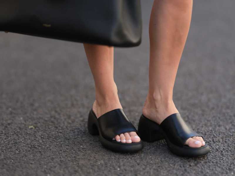 Schwarze Sandalen und lackierte Fußnägel