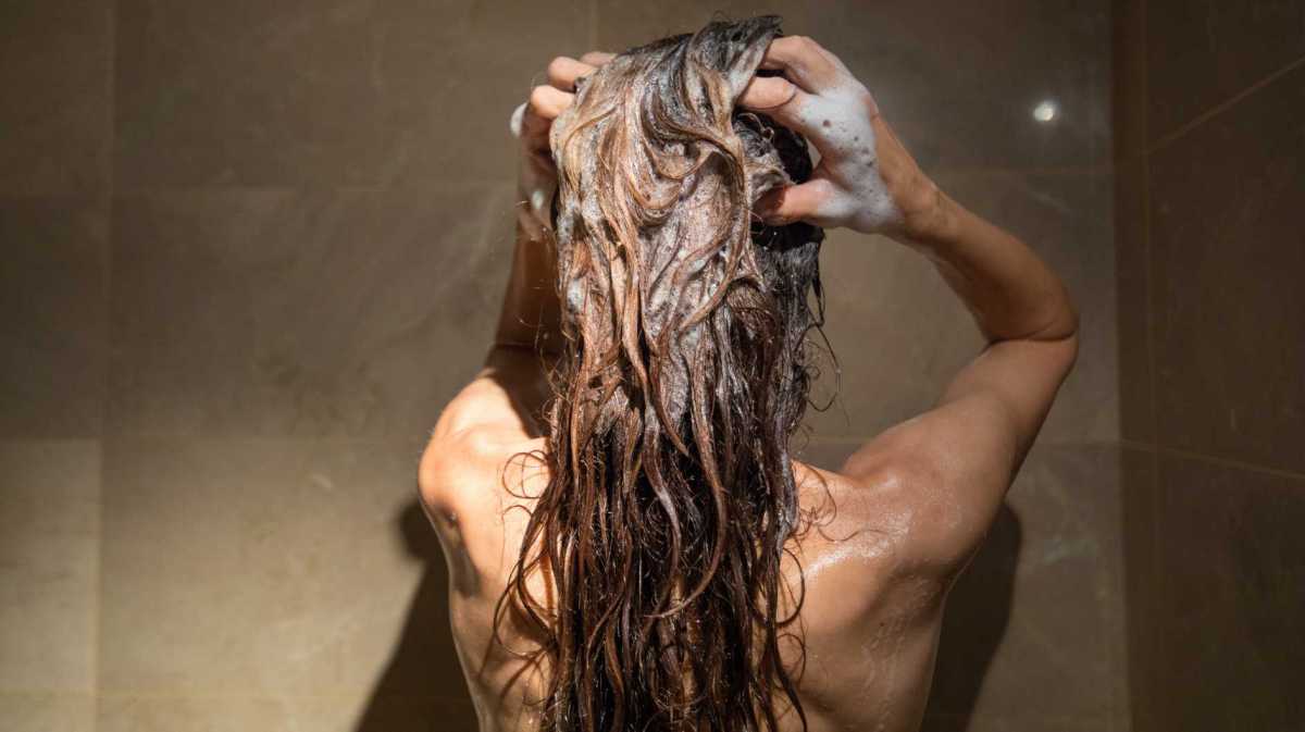 Frau wäscht sich unter der Dusche die Haare