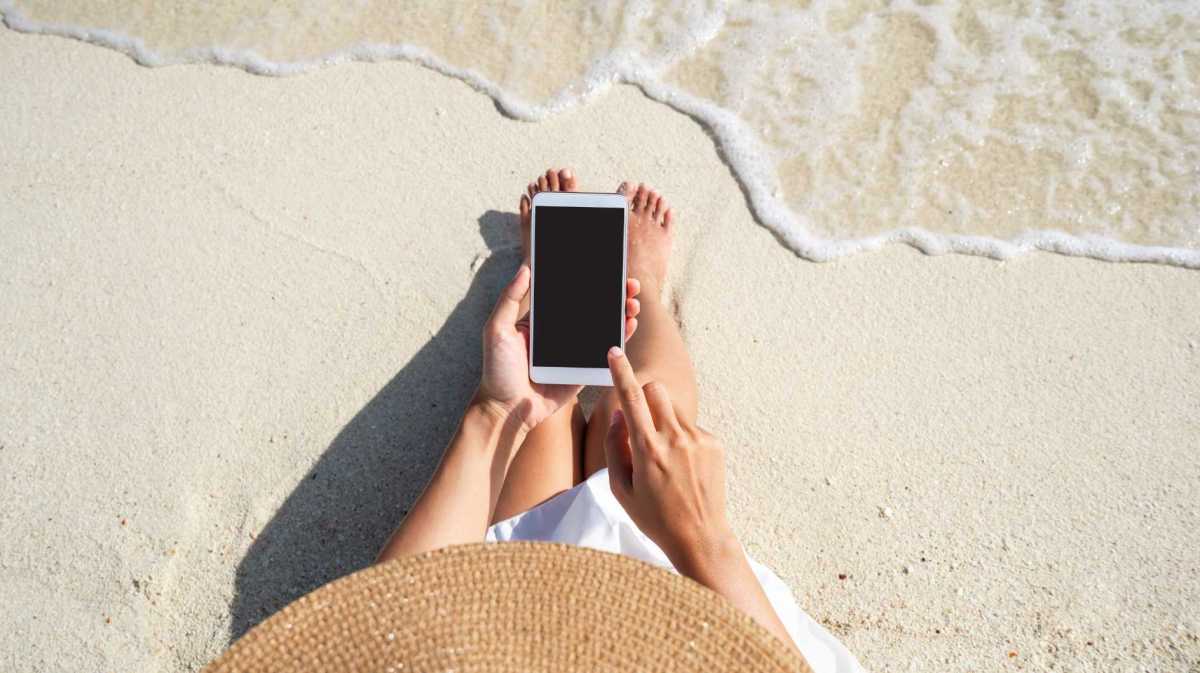 Frau benutzt ihr Handy am Strand