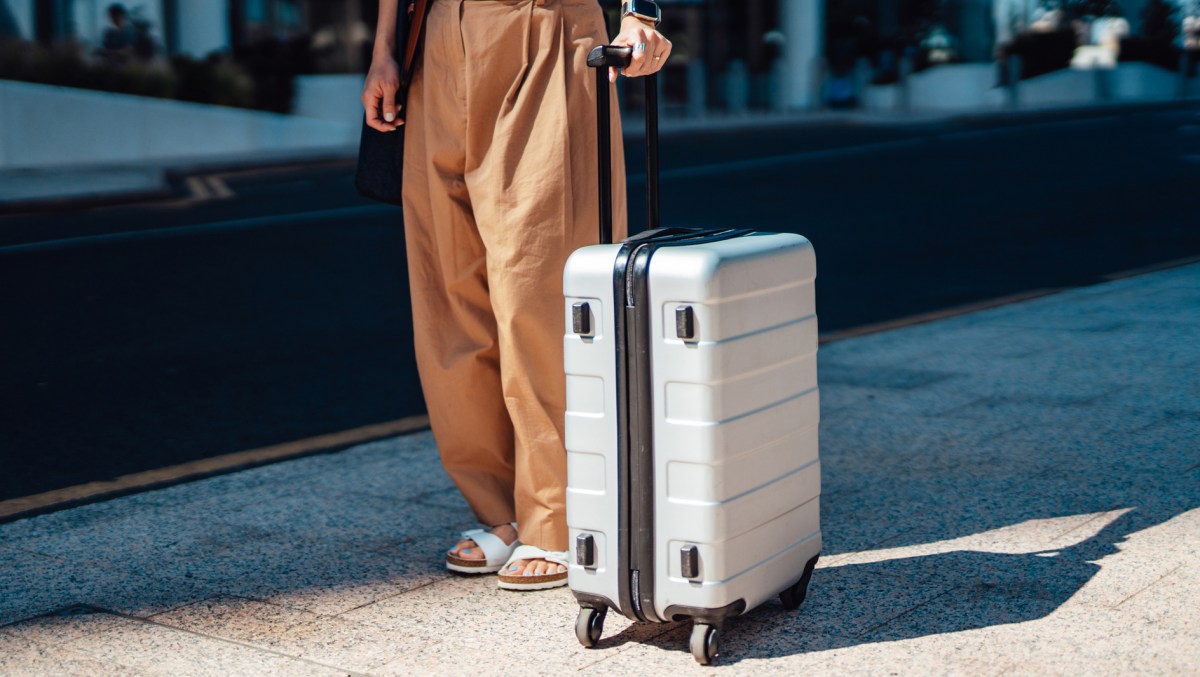 Frau steht mit Koffer am Bahsteig