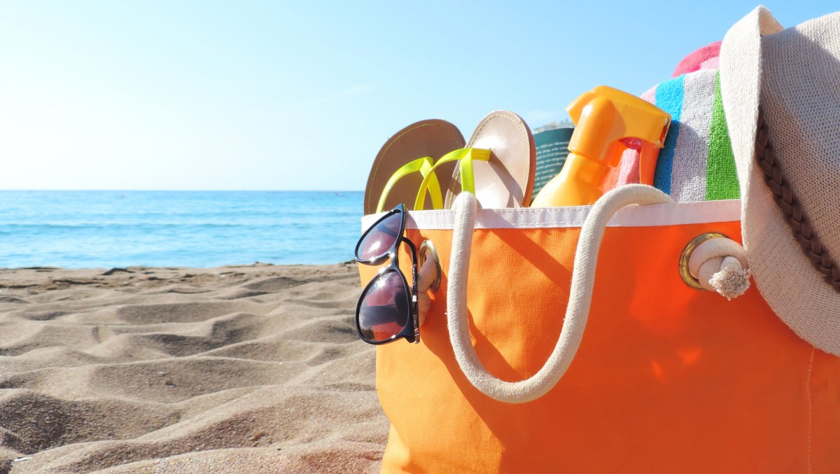Strandtasche in Orange steht am Strand.