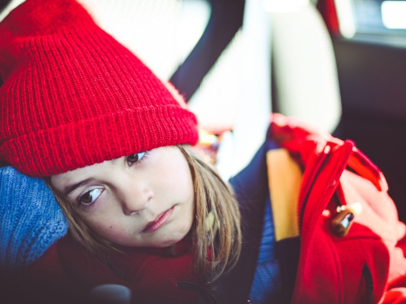 Mädchen sitzt müde im Auto.