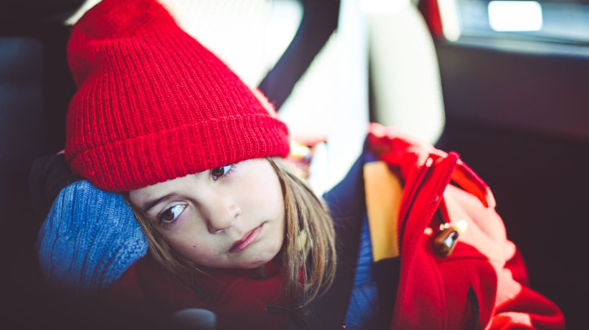 Mädchen sitzt müde im Auto.