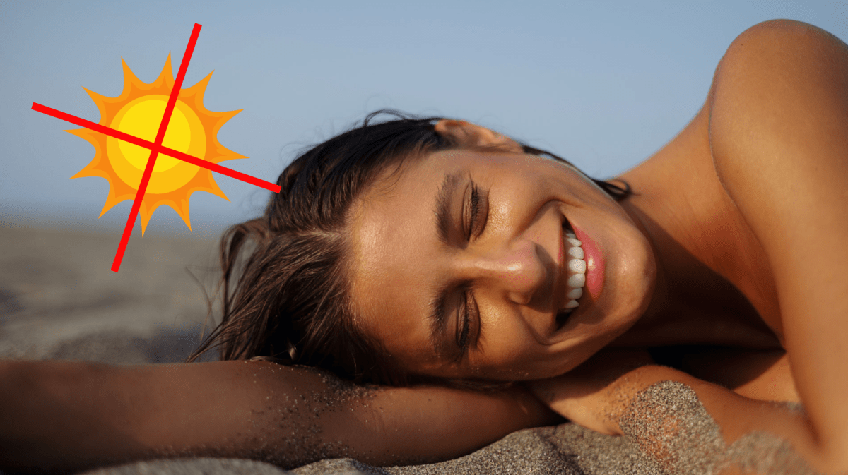 Frau, die im Sand liegt und sehr braun ist.