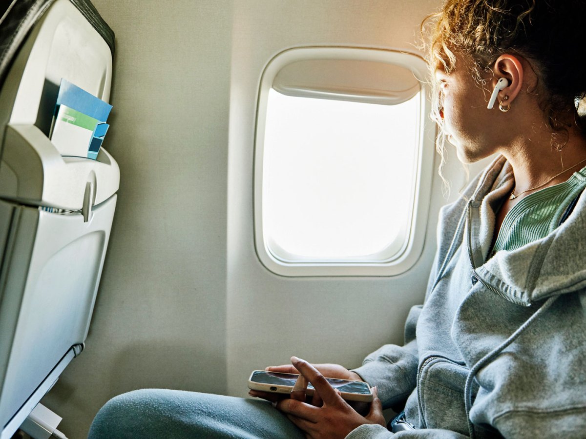 Frau im Flugzeug mit Handy in der Hand
