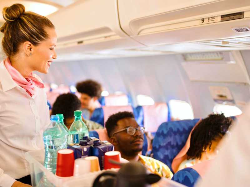 Flugbegleiterin mit Trolley im Flugzeug.