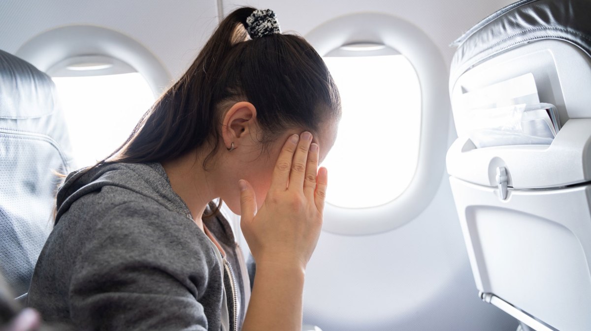Frau mit Händen am Gesicht in Flugzeug