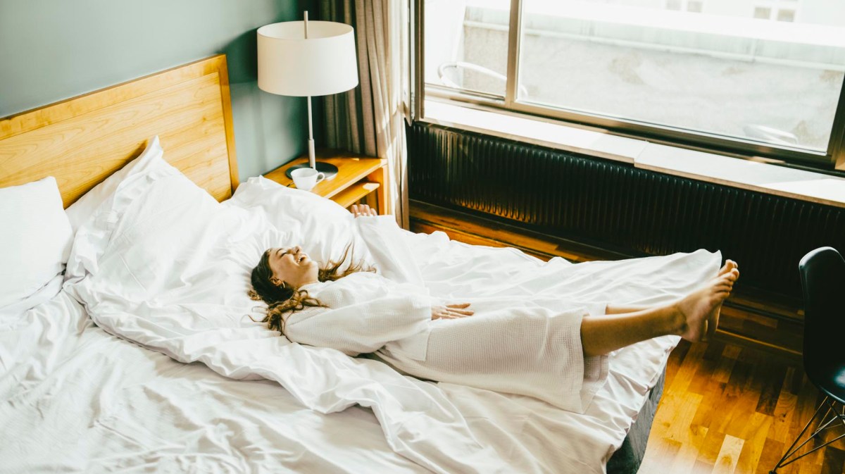 Frau lässt sich im Hotel aufs Bett fallen
