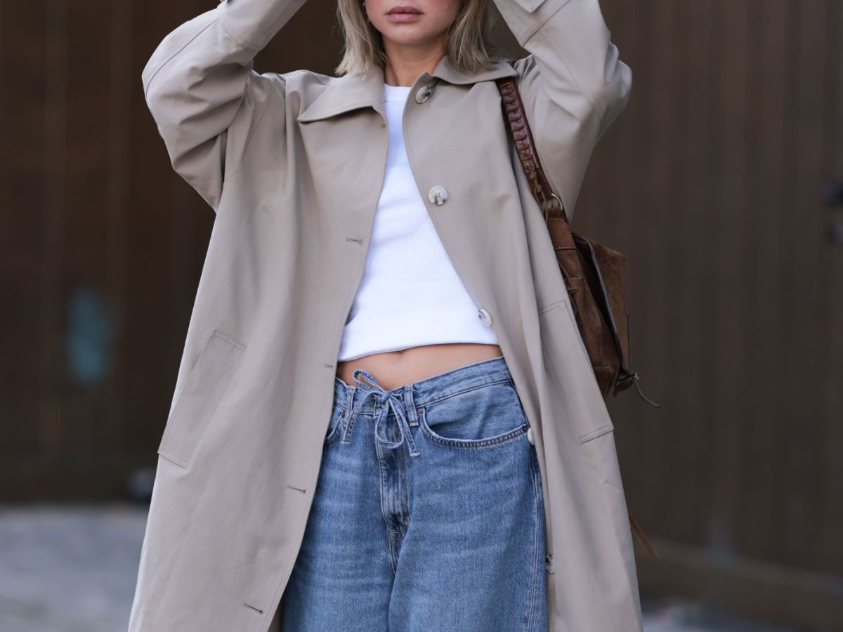 Streetstyle von Sophia Geiss in beigem Trenchcoat, weißem Crop Top und blauer Jeans mit Kordelzug
