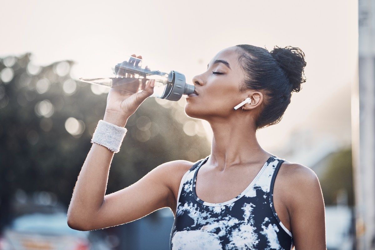Weibliche Person, Outdoor und Übung Pause mit Flasche Wasser, städtische Umgebung und Kopfhörer für Sport Musik