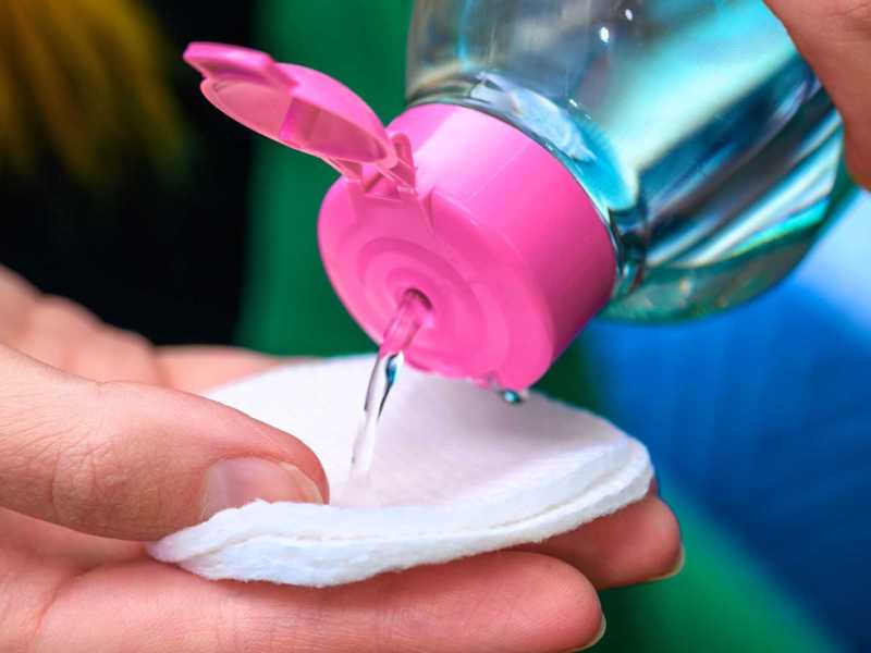 Person schüttet Nagellackentferner auf Wattepad - Nahaufnahme.