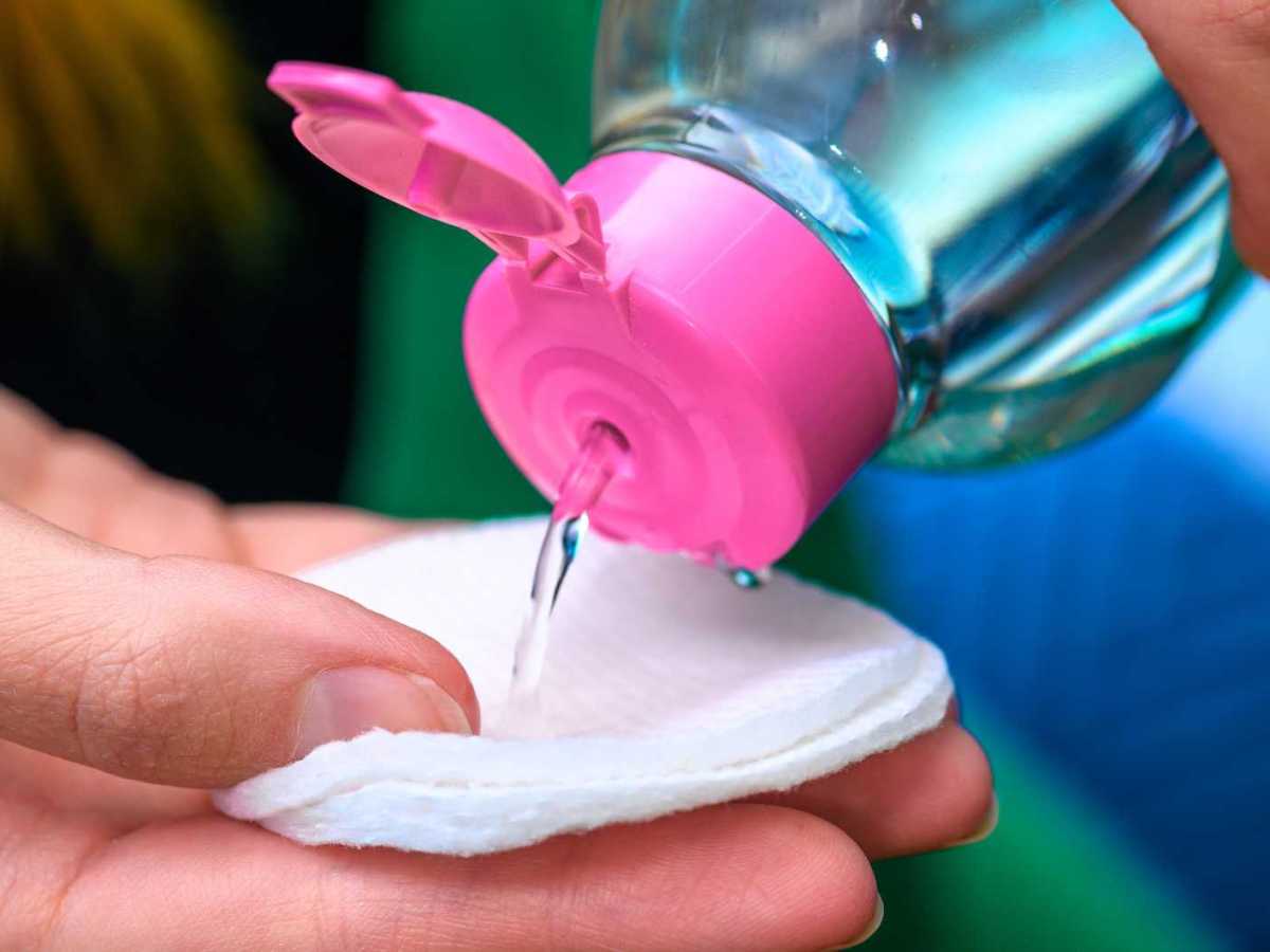 Person schüttet Nagellackentferner auf Wattepad - Nahaufnahme.