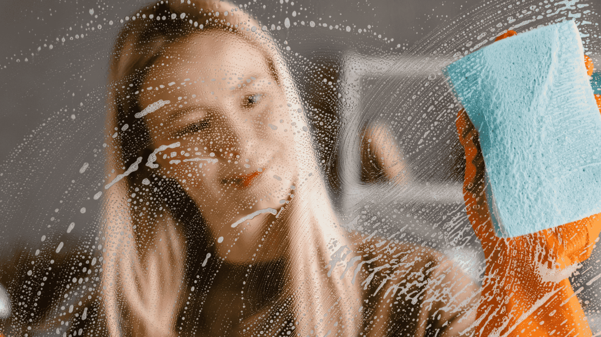 Frau putzt Fenster mit Tuch.