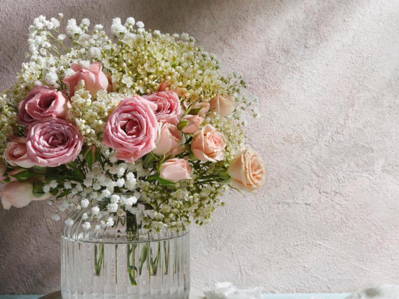 Blumenstrauß mit Rosen und Schleierkraut in einer Vase.