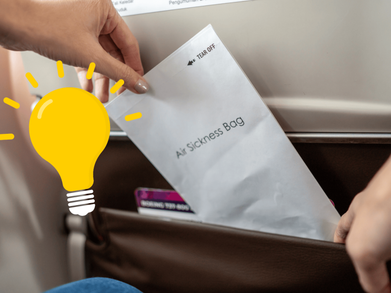 Person zieht Spuckbeutel aus Vordersitz im Flugzeug.