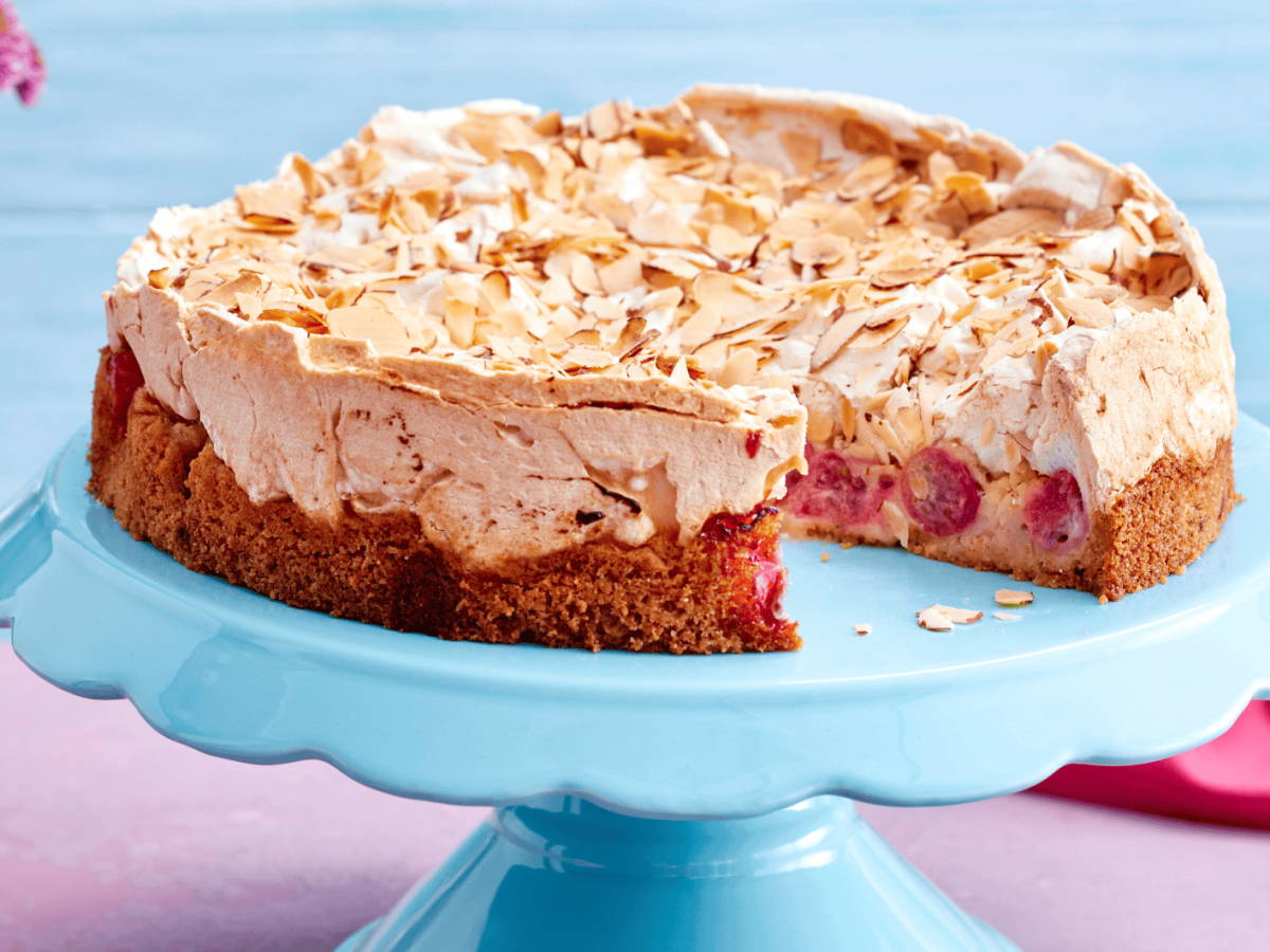 Stachelbeerkuchen mit Baiserhaube auf blauem Kuchenst&auml;nder.