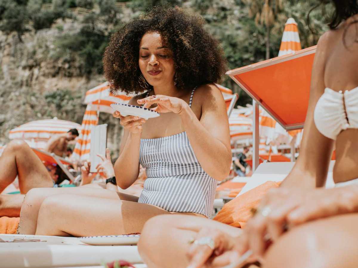 Junge Frau isst am Strand.