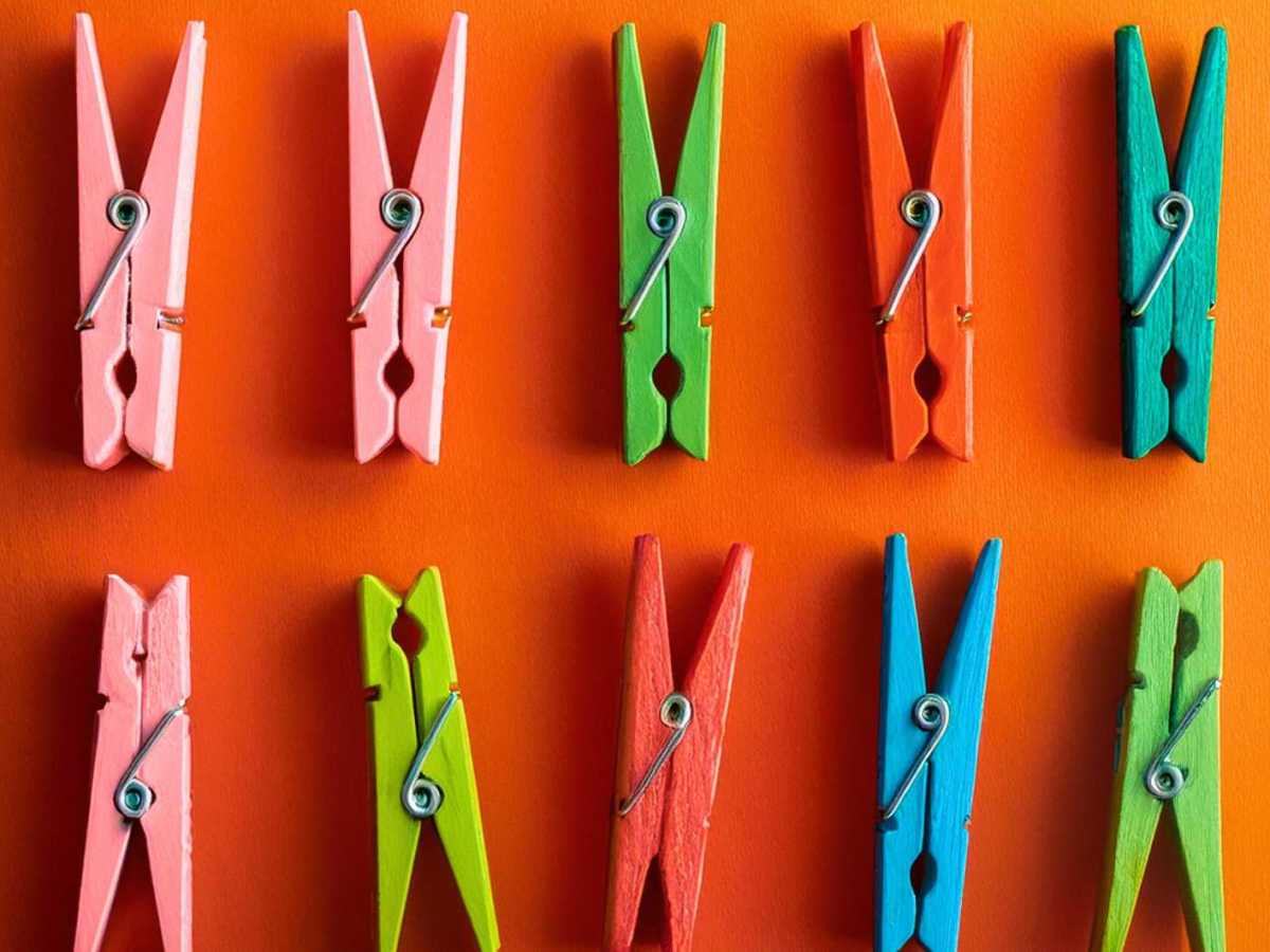 Bunte W&auml;scheklammern auf orangenem Hintergrund.