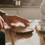 Frau schmiert sich ein Brot.