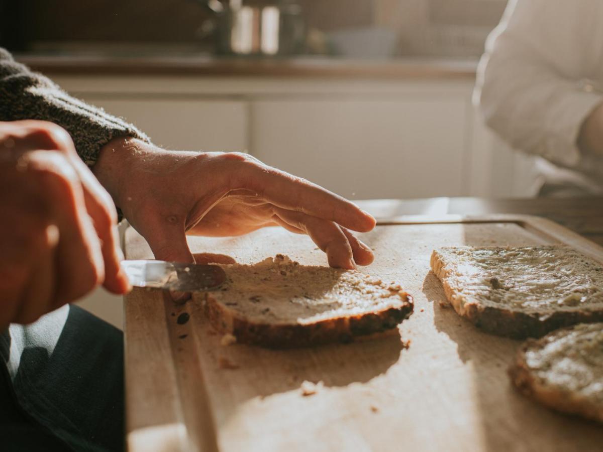 Frau schmiert sich ein Brot.