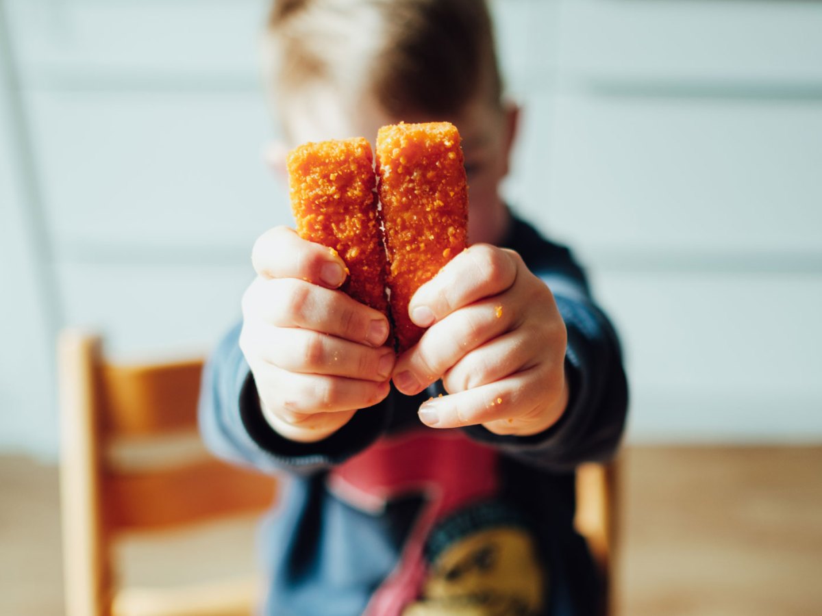 Kind hält zwei Fischstäbchen in die Kamera.