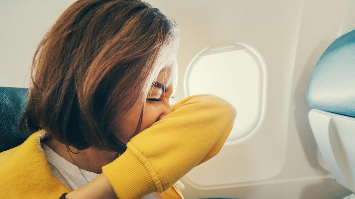 Frau mit einem gelben Pullover nießt in den