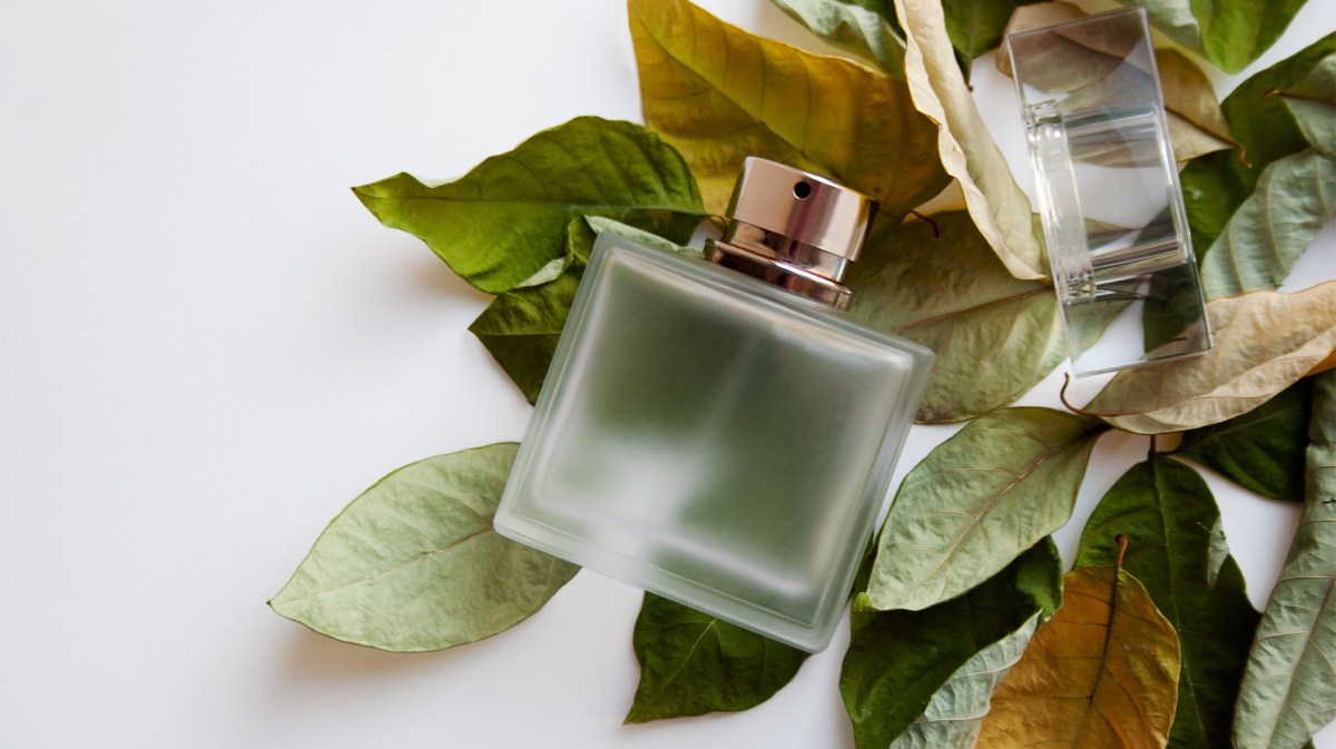 Parfum-Flakon, der auf getrockneten Herbst-Blättern liegt.