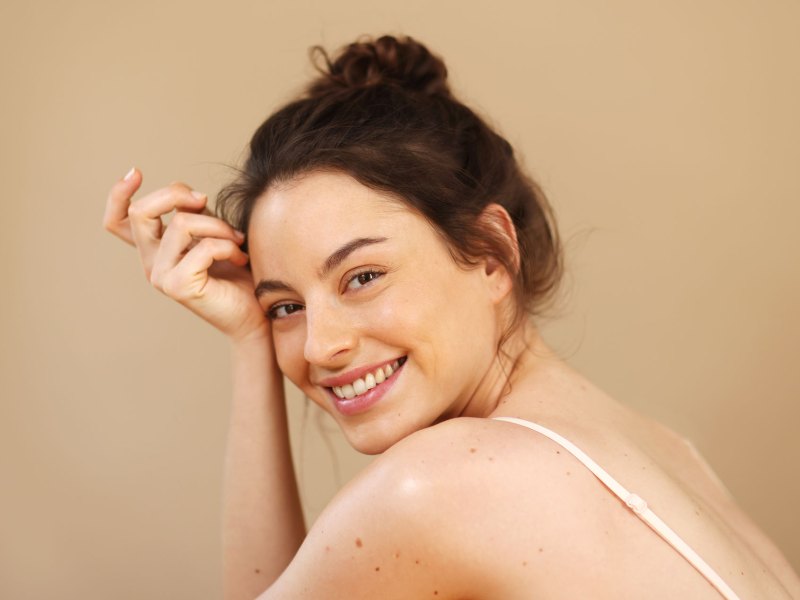 Frau mit gepflegter Haut, die in die Kamera lächelt.