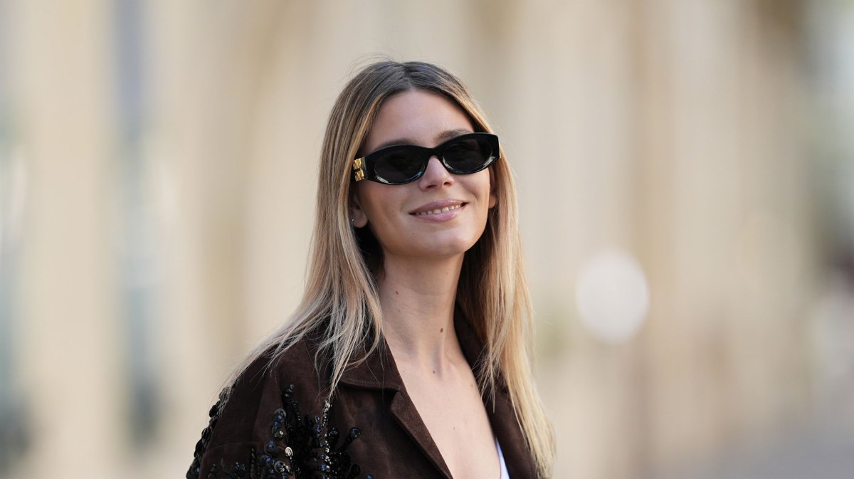 Lächelnde Frau im Herbst mit einer brauen Jacke.