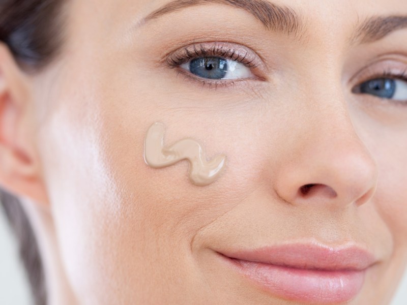 Frau, die einen Klecks Make-up auf ihr Gesicht aufgetragen hat.