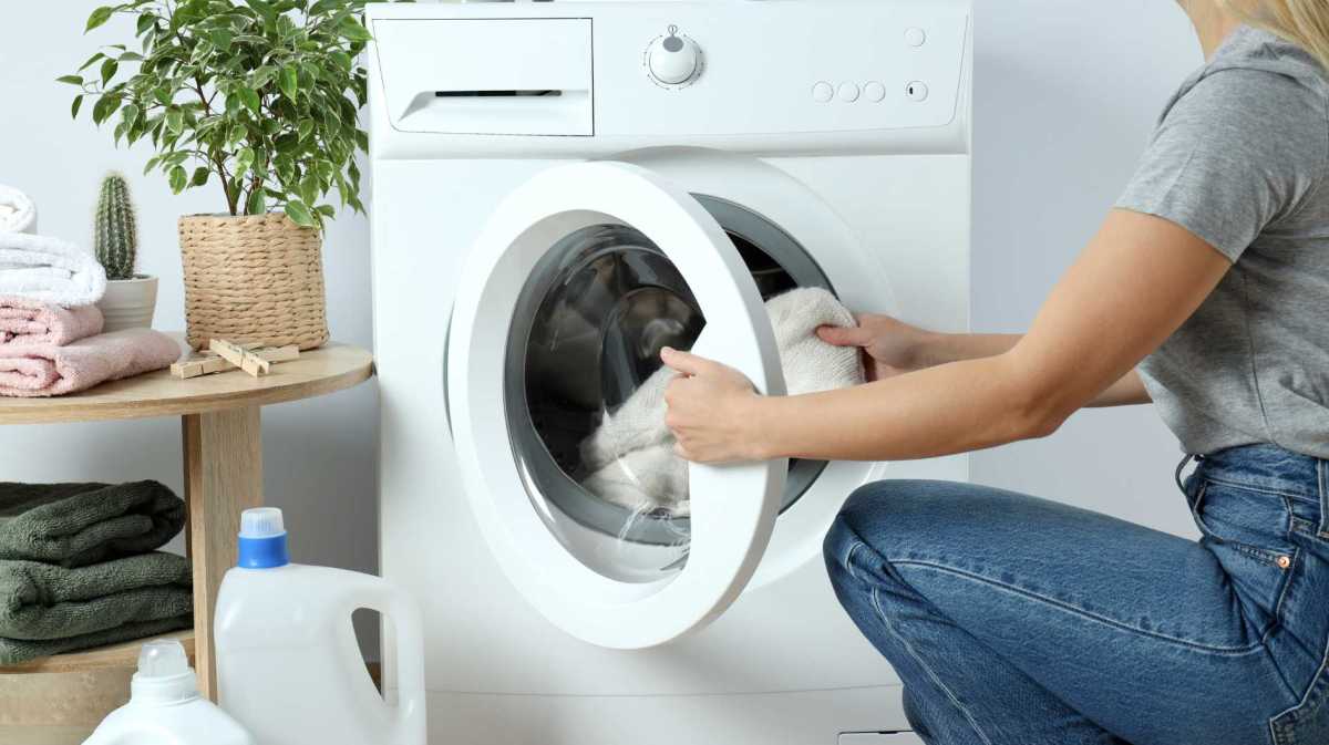 Frau steckt Kleidung in die Waschmaschine