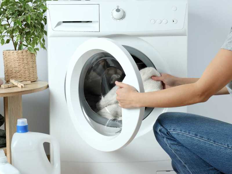 Frau steckt Kleidung in die Waschmaschine