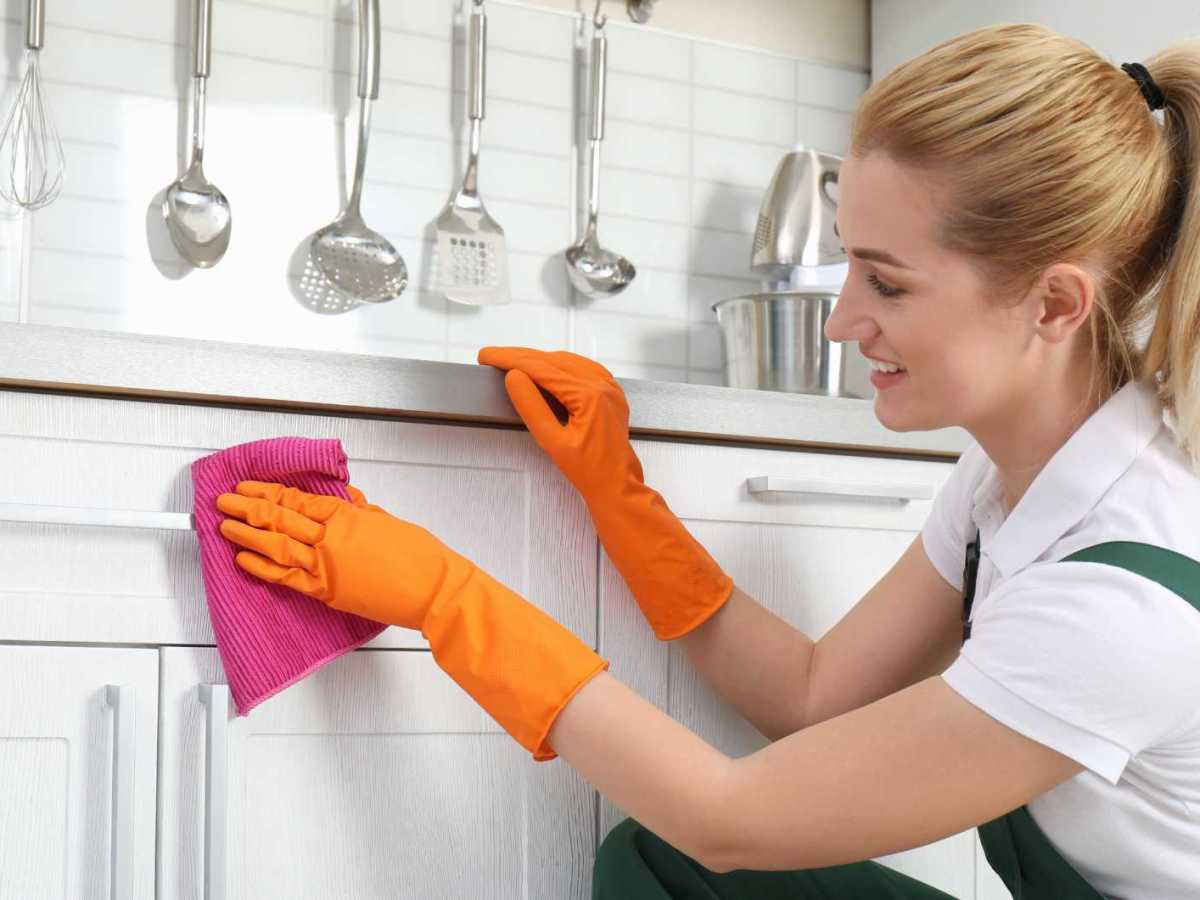 Frau wischt Küchenfronten mit einem Lappen ab
