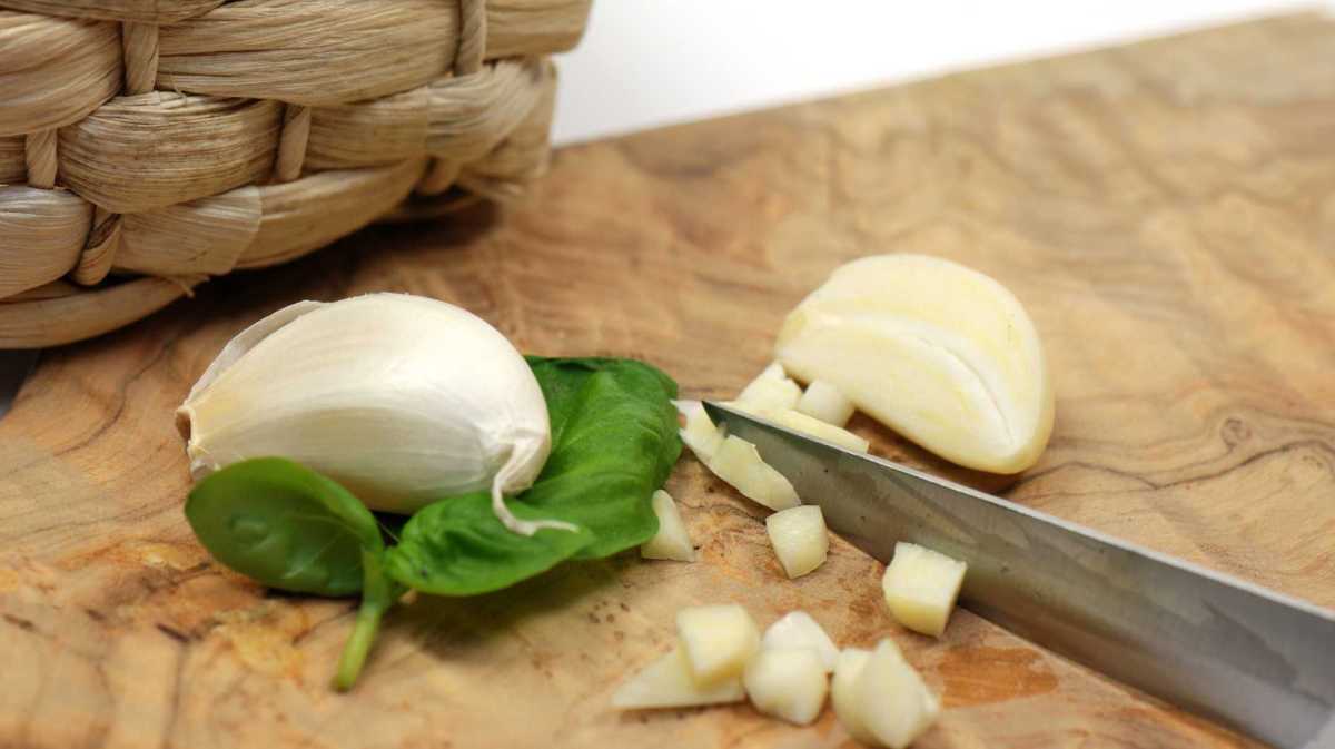 Knoblauch wird auf einem Schneidebrett geschnitten